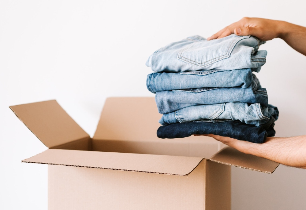 person putting folded jeans into a box. Photo.