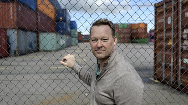 Man standing next to chain link fence. Photo. 
