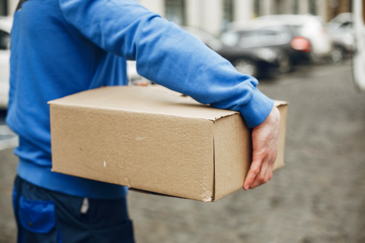 Person carrying a box under their arm. Photo. 