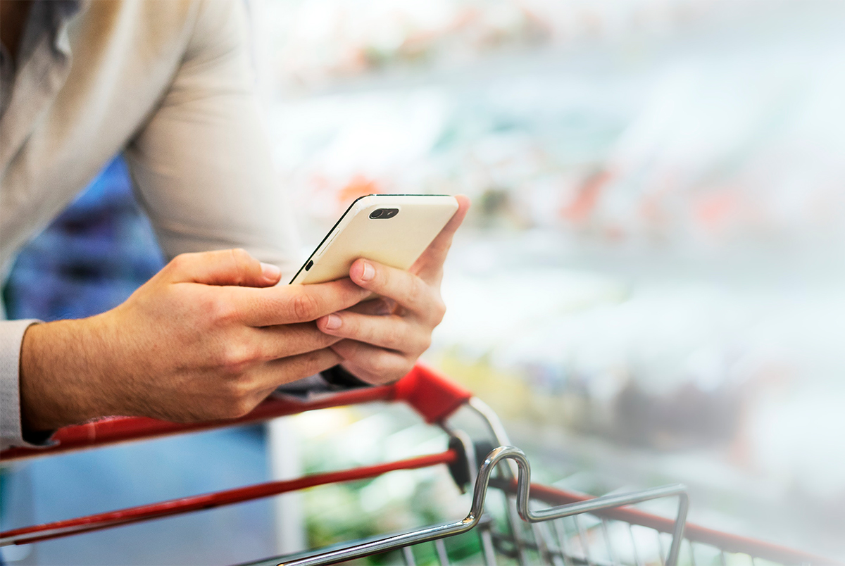 person with smartphone leaning over a shopping cart. photo. 