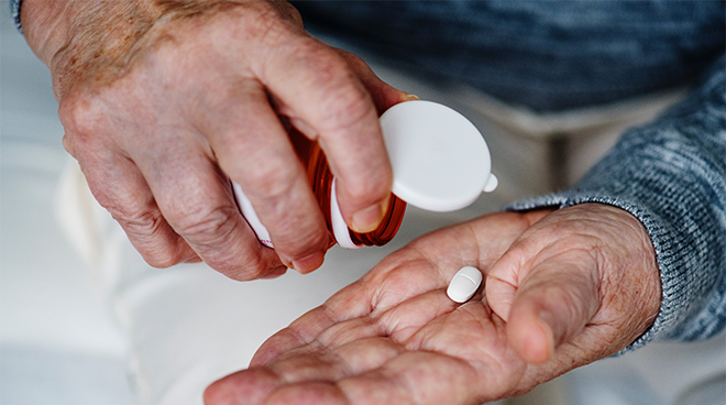 elderly person pouring pills into their hand from a bottle. Photo. 